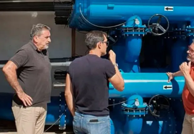 Técnicos de Vicama Ingenieros revisando un cabezal de riego con filtros y válvulas en una caseta de bombeo