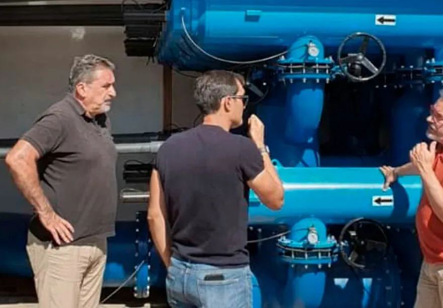 Tres técnicos de Vicama Ingenieros revisando el cabezal de filtrado y las válvulas de una instalación de riego